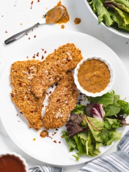 Crispy golden chicken strips on a plate with crisp fresh salad