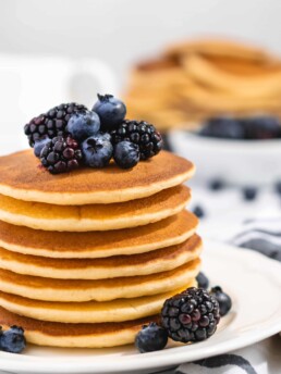 Fluffy Golden Buttermilk Pancakes stacked high, topped with fresh berries