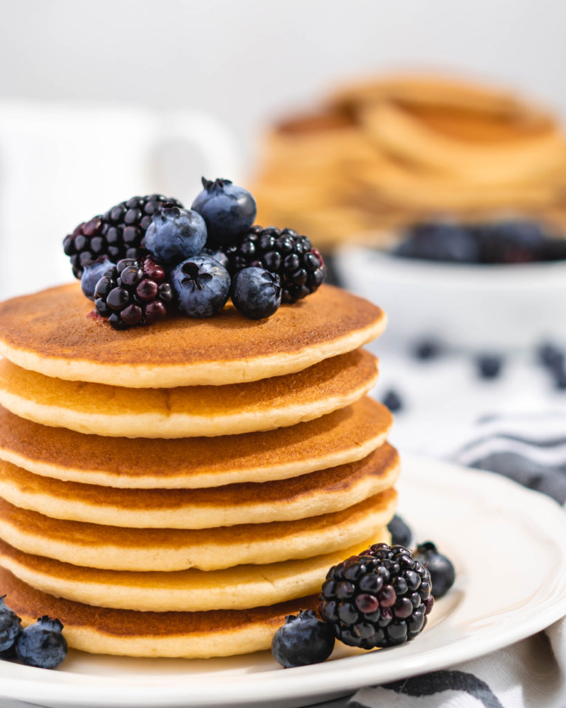 Fluffy Golden Buttermilk Pancakes stacked high, topped with fresh berries