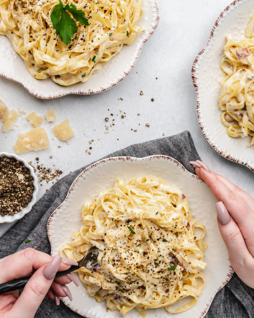 Creamy pasta carbonara is topped with fresh parsley and crispy pancetta