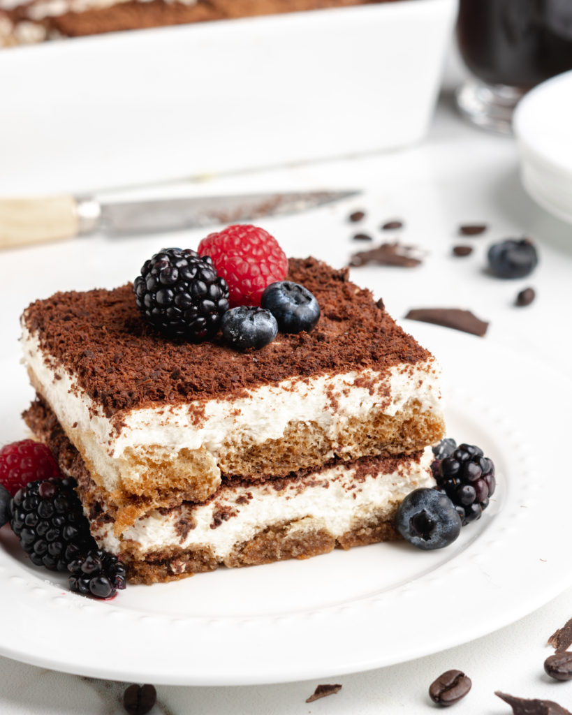 A slice of delicious creamy no-bake tiramisu is topped with fresh plump berries