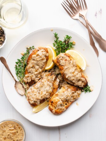 Chicken breasts on a plate, topped with white wine cream sauce