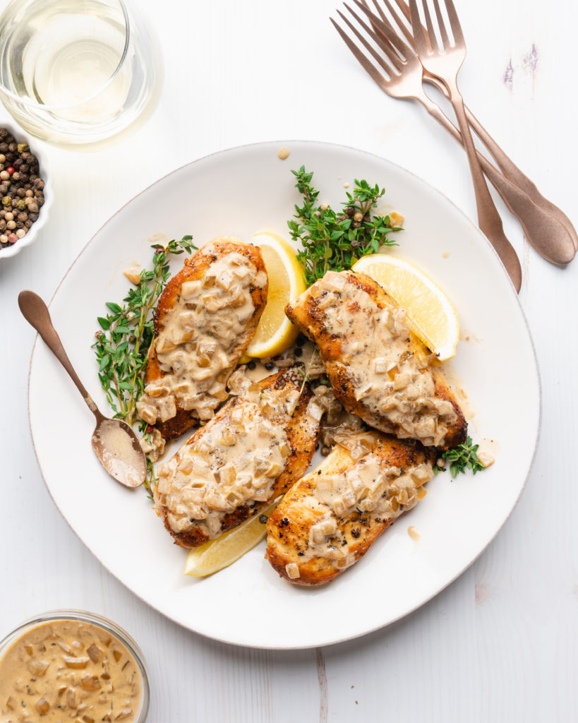 Chicken breasts on a plate, topped with white wine cream sauce