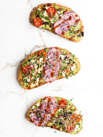 Mashed avocado is spread onto a toasted piece of bread, then topped with juicy tomatoes, sweet spicy sriracha, and salty feta!