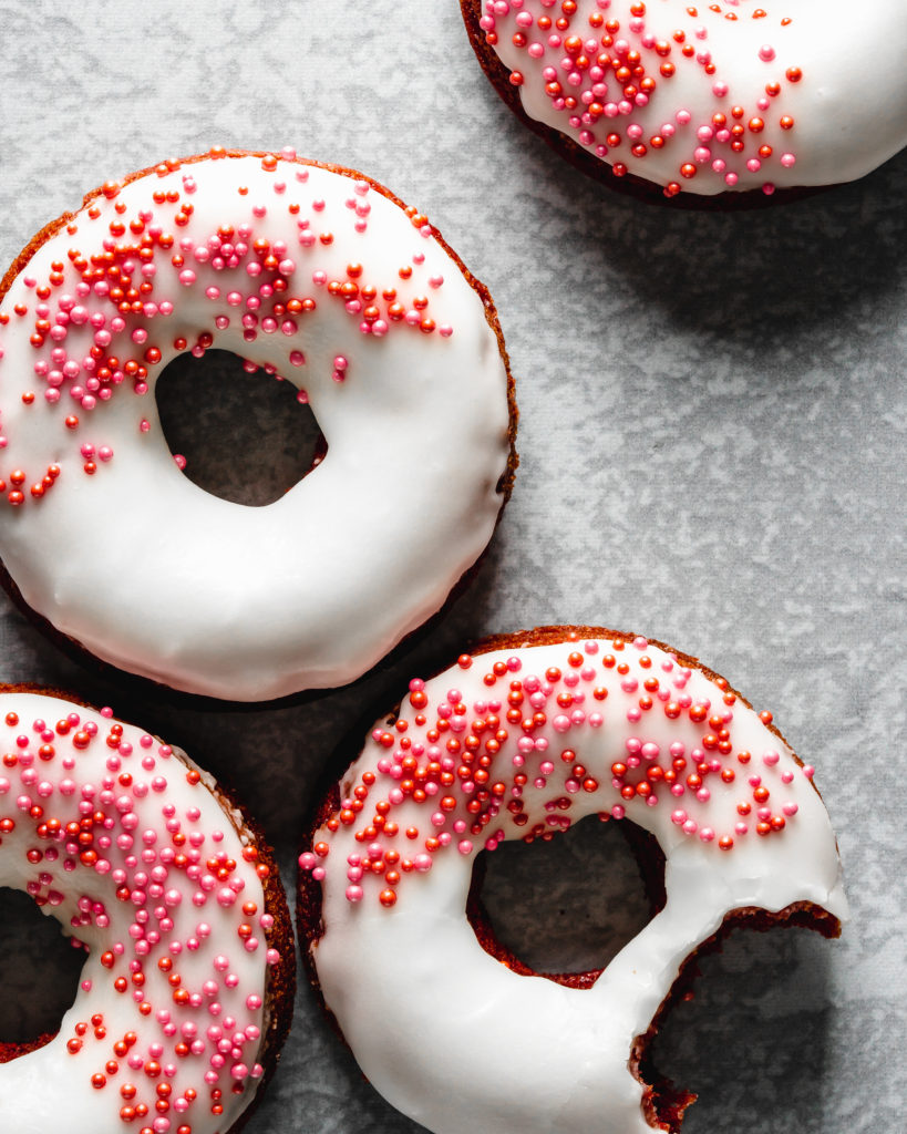 Easy to make baked red velvet donuts are glazed with a cream cheese frosting