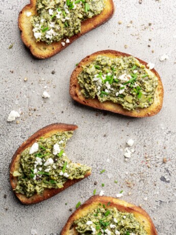 Creamy bright green spinach dip and artichoke dip, topped with feta cheese and chives and served warm