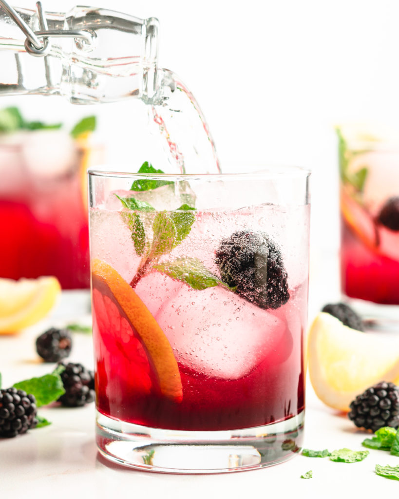 Blackberry syrup, added to lemon juice and vodka, then topped with club soda. Garnished with aromatic fresh mint, for a delicious blackberry vodka cocktail.