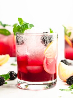Blackberry syrup, added to lemon juice and vodka, then topped with club soda. Garnished with aromatic fresh mint, for a delicious blackberry vodka cocktail.