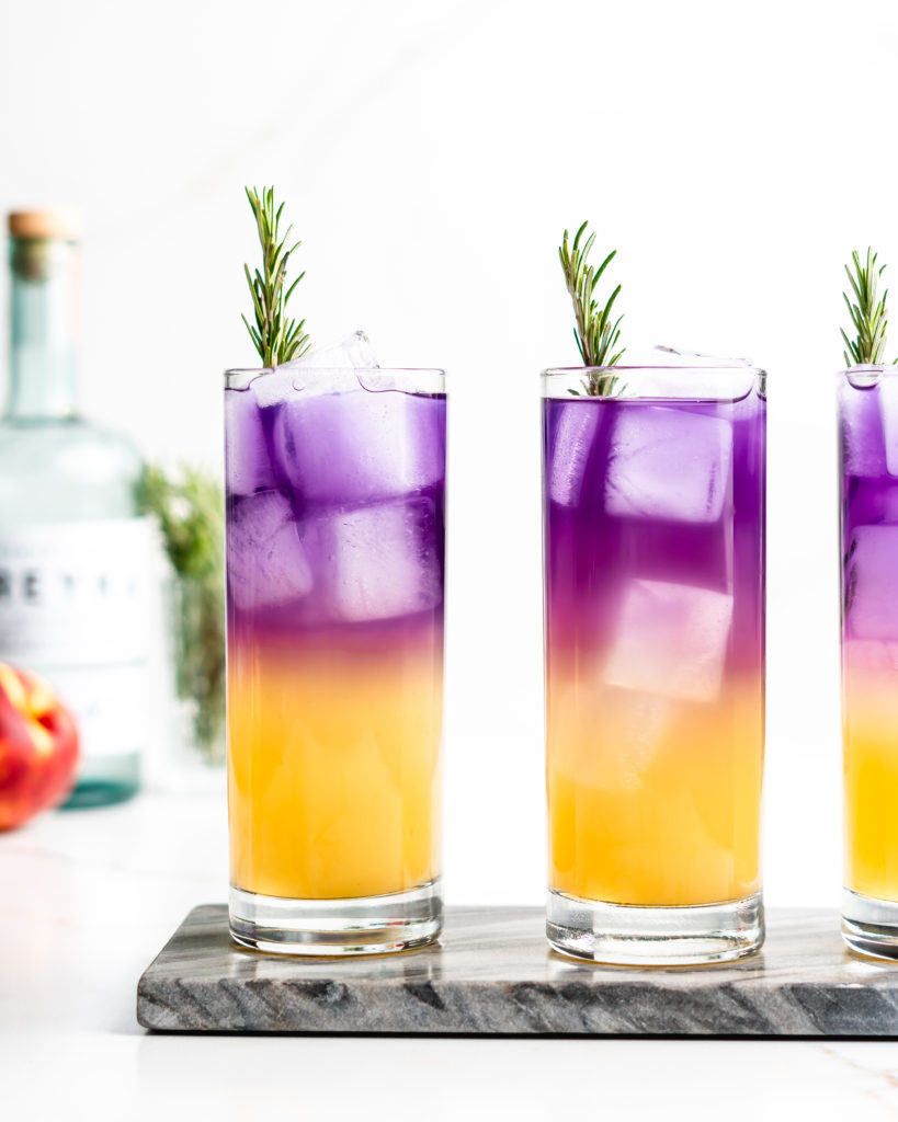 This vibrant cocktail features vodka, peach syrup, yuzu juice, sake, butterfly pea flower tea, and soda water. Garnished with fragrant rosemary.