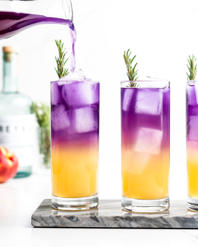 This vibrant cocktail features vodka, peach syrup, yuzu juice, sake, butterfly pea flower tea, and soda water. Garnished with fragrant rosemary.
