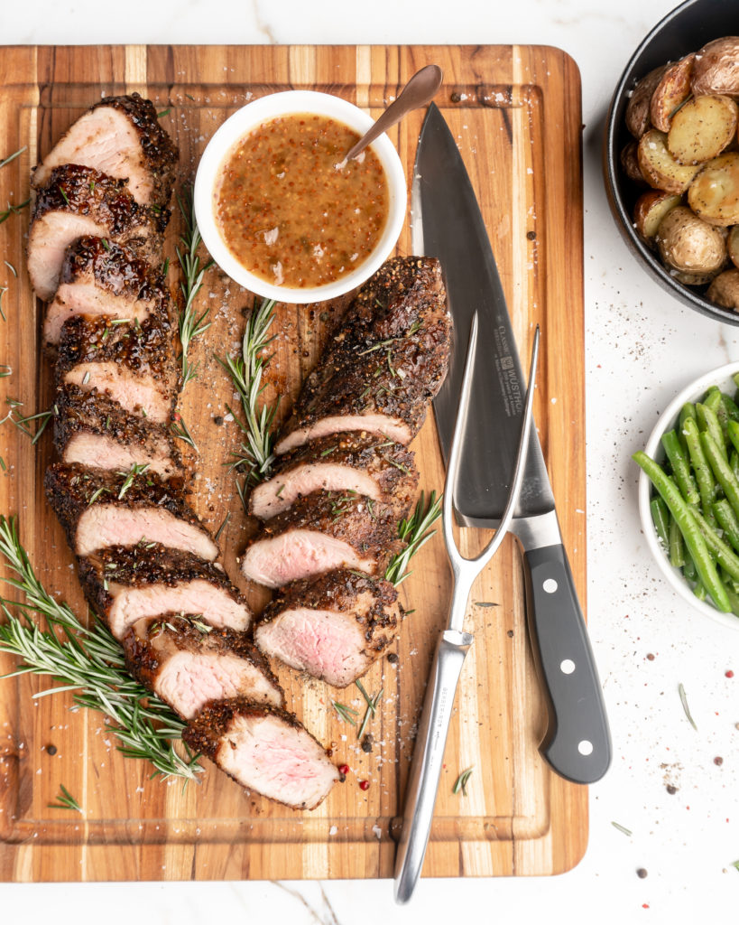Pork tenderloin is crusted with peppercorns and then glazed with a rosemary peach mustard sauce.