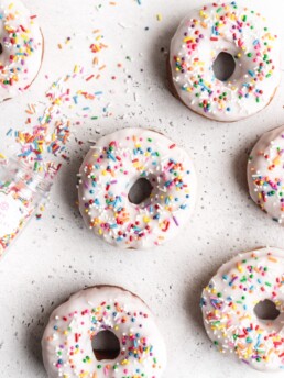 Perfectly cut donuts are made with brown butter and vanilla to amp up the flavor. Frosted with white glaze and rainbow sprinkles