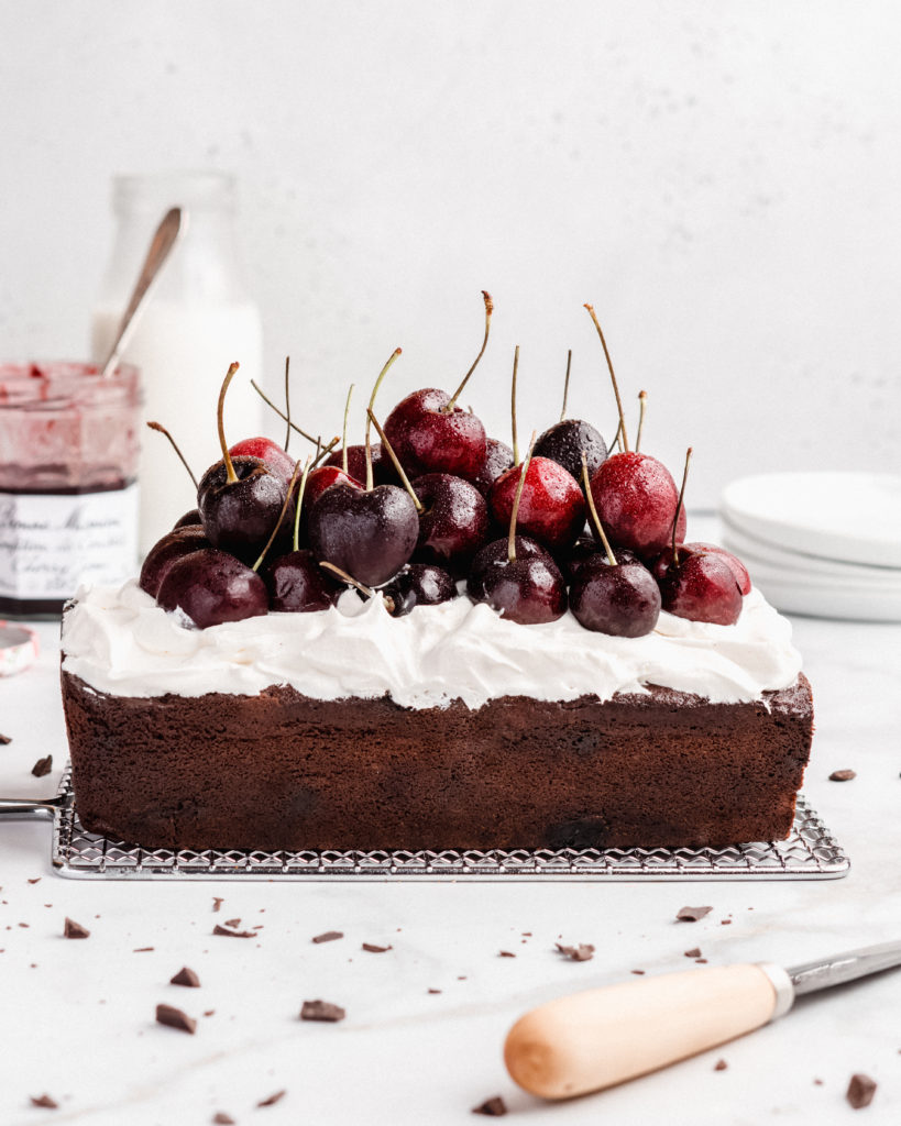 Rich chocolate loaf cake is swirled with cherry jam, then topped with fresh whipped cream and fresh cherries