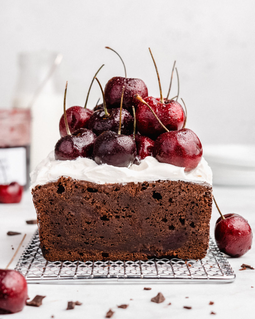 Rich chocolate loaf cake is  swirled with cherry jam, then topped with fresh whipped cream and fresh cherries