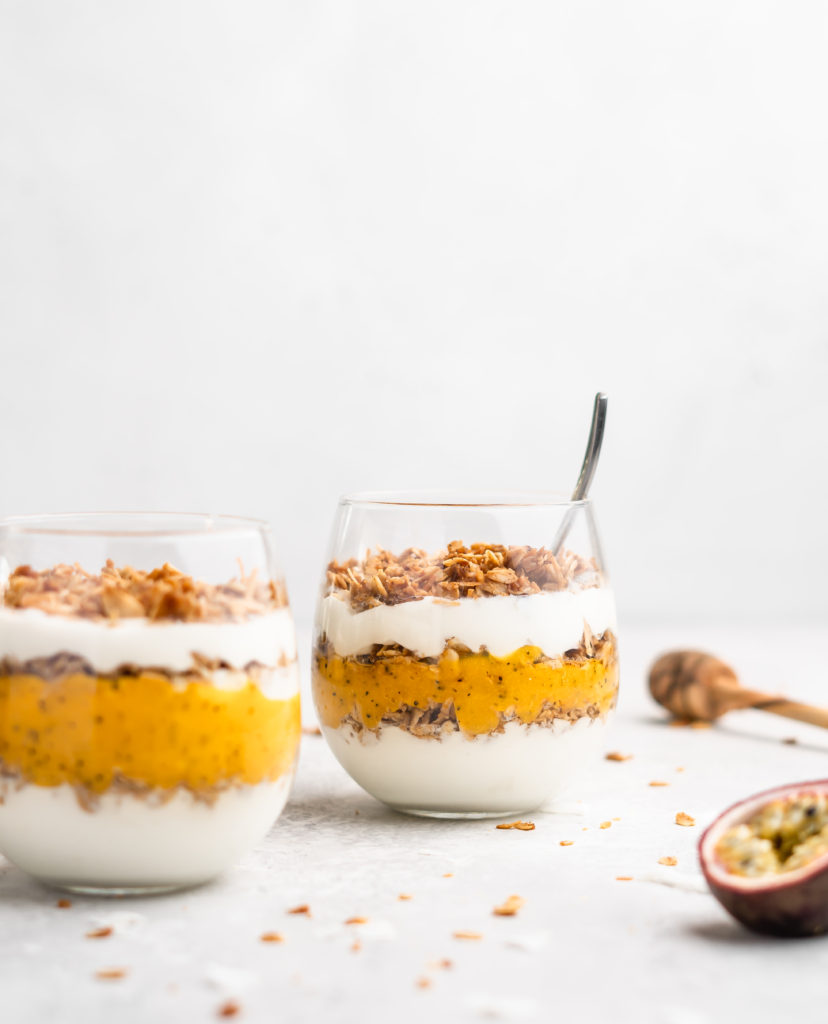 Layers of passion fruit and mango puree, yogurt, and coconut granola make up with tropical yogurt parfait