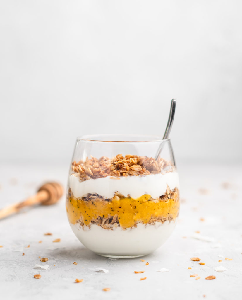 Layers of passion fruit and mango puree, yogurt, and coconut granola make up with tropical yogurt parfait