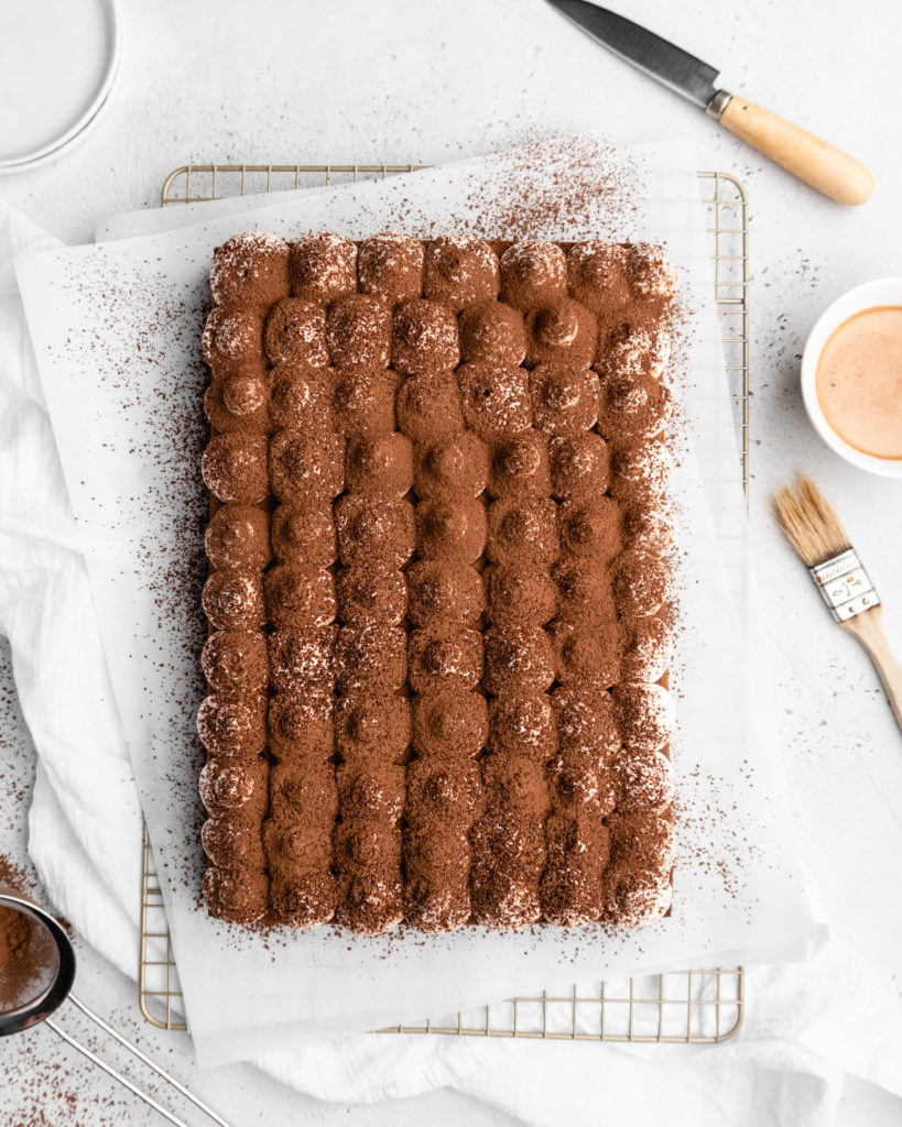 Espresso and vanilla infused sheet cake is brushed with a kahlua coffee simple syrup, and then topped with a creamy mascarpone whipped cream in this Tiramisu Sheet Cake