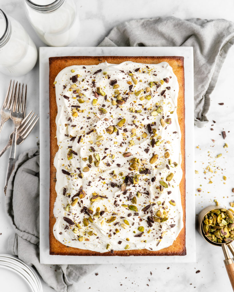 Cannoli Cake that is topped with creamy whipped ricotta frosting, then sprinkled with chocolate and pistachios