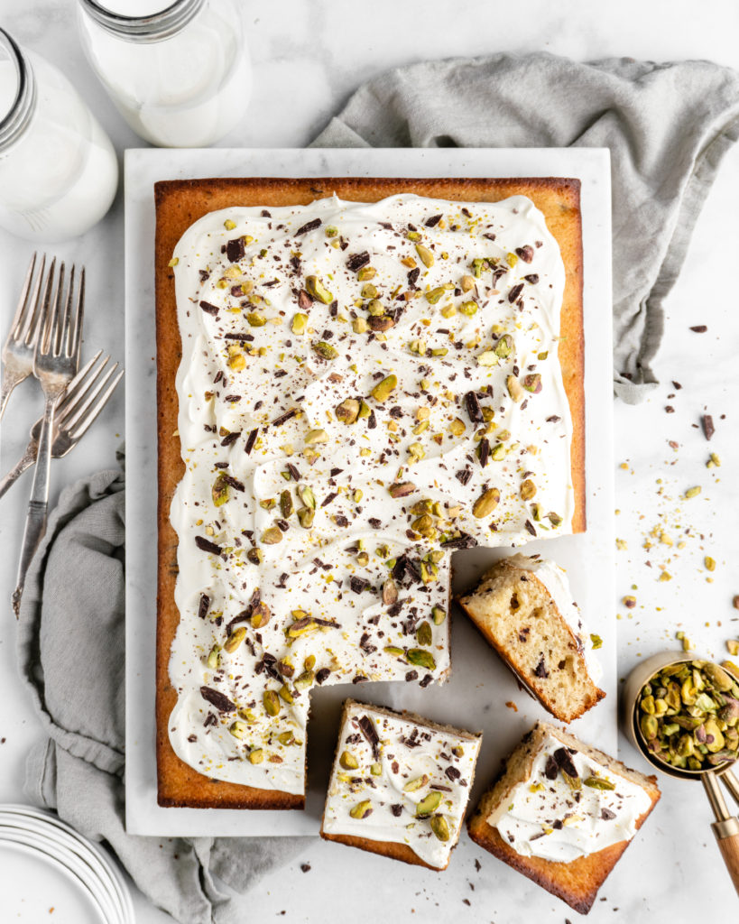 Cannoli Cake that is topped with creamy whipped ricotta frosting, then sprinkled with chocolate and pistachios