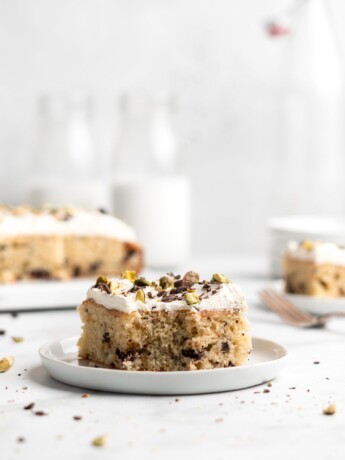 Cannoli Cake that is topped with creamy whipped ricotta frosting, then sprinkled with chocolate and pistachios