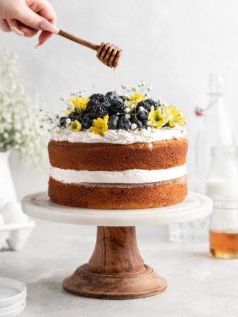 2 layer naked styled chamomile and honey infused cake is decorated with berries and flowers