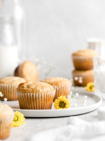 Light and fluffy one bowl lemon poppy seed muffins in white wrappers on a plate