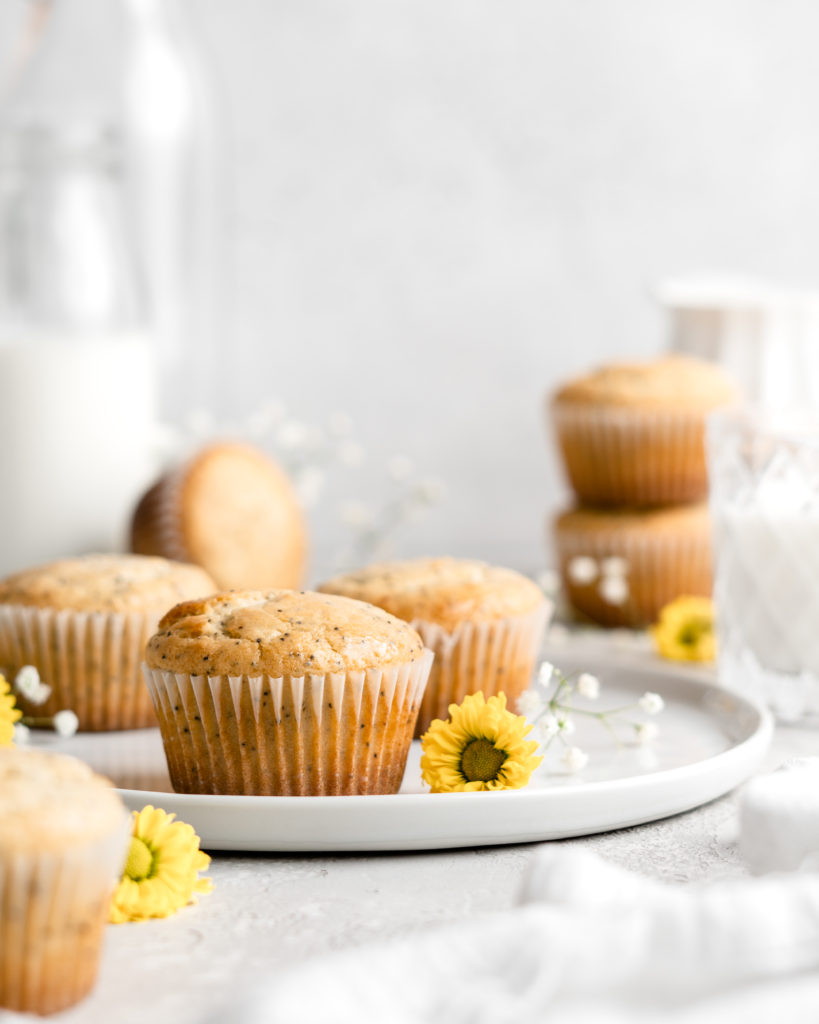 Light and fluffy one bowl lemon poppy seed muffins in white wrappers on a plate