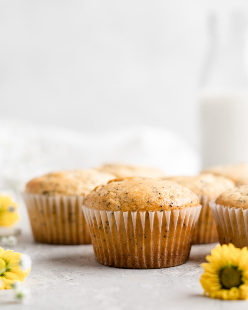 Light and fluffy one bowl lemon poppy seed muffins in white wrappers on a plate