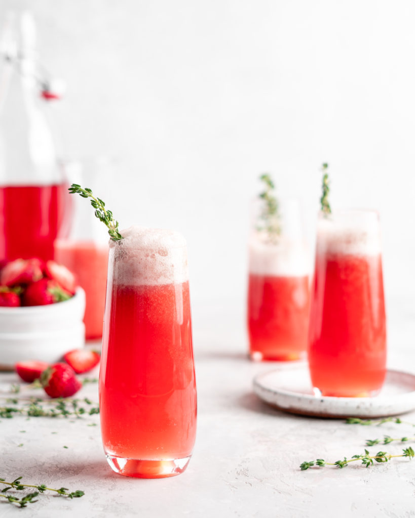 Bright red strawberry guava juice is mixed with sparkling rose wine in stemless champagne glasses to make Strawberry Guava Mimosa