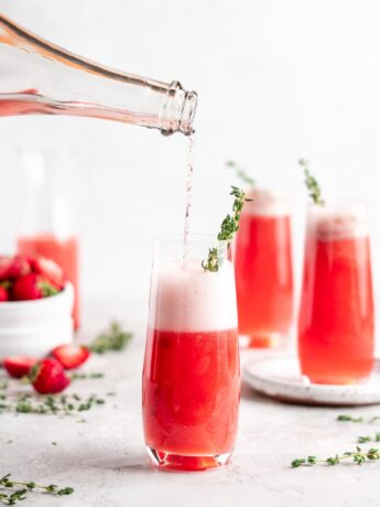 Bright red strawberry guava juice is mixed with sparkling rose wine in stemless champagne glasses to make Strawberry Guava Mimosa