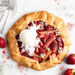 Flaky golden pie dough is folded into a galette shape over a strawberry rhubarb filling