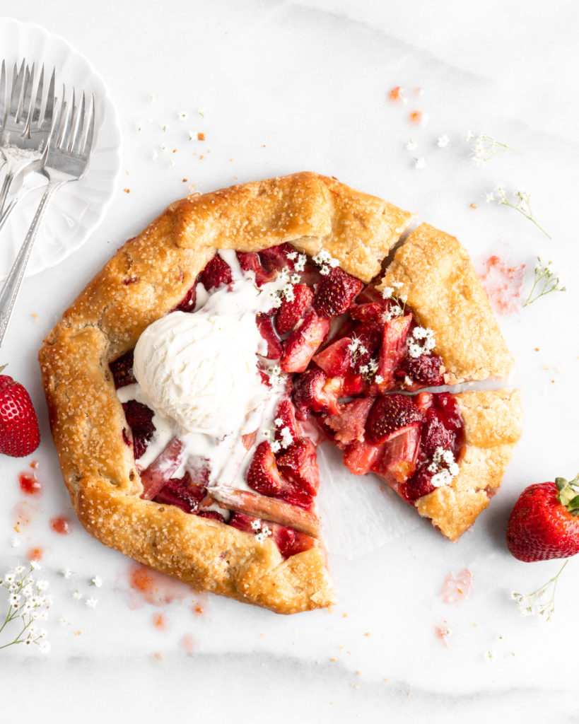 Flaky golden pie dough is folded into a galette shape over a strawberry rhubarb filling