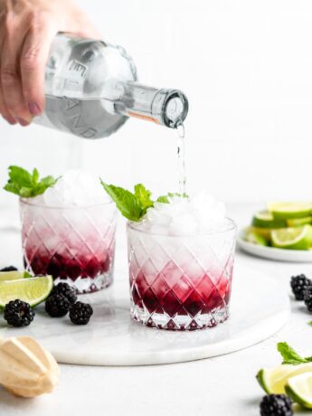 This blackberry rhubarb cocktail features a blackberry rhubarb syrup, soda water, vodka, mint, and lime