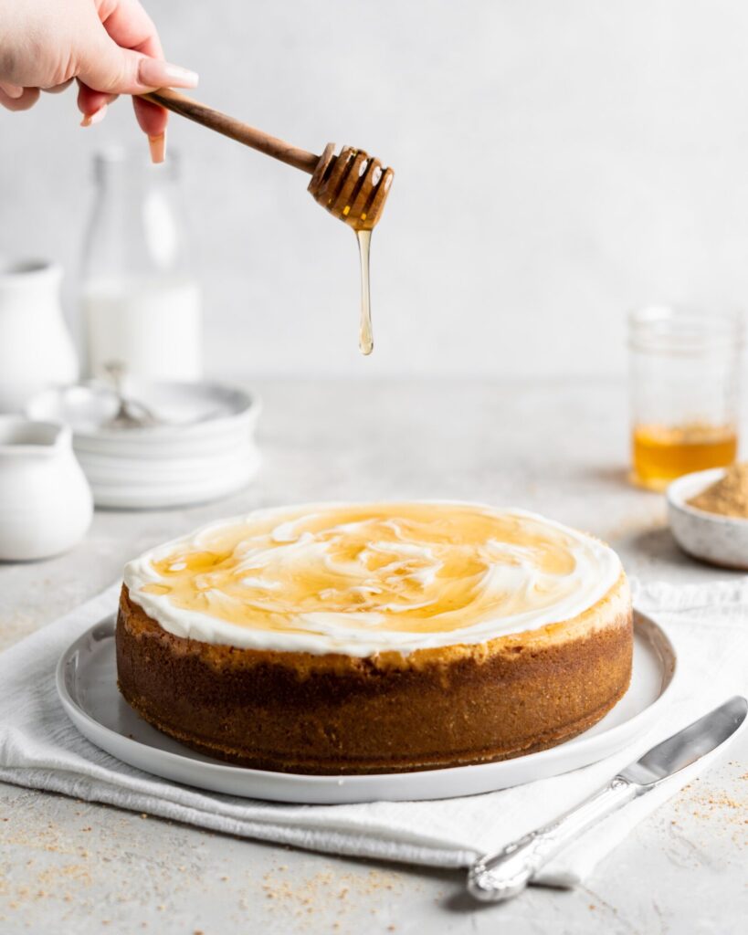 Creamy Salted Honey Cheesecake has a graham cracker crust and a sour cream topping. Drizzled with additional salted honey