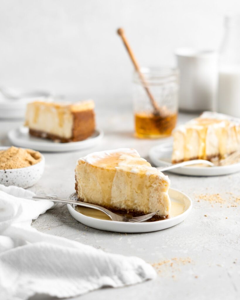 Creamy Salted Honey Cheesecake has a graham cracker crust and a sour cream topping. Drizzled with additional salted honey