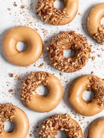 Baked Spiced Brown Sugar Donuts are glazed in a butter maple glaze and garnished with a crushed pecan crust