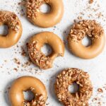 Baked Spiced Brown Sugar Donuts are glazed in a butter maple glaze and garnished with a crushed pecan crust