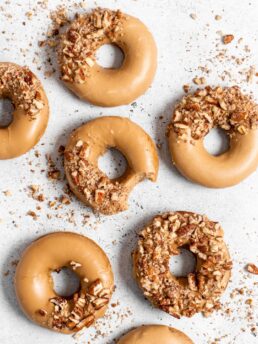 Baked Spiced Brown Sugar Donuts are glazed in a butter maple glaze and garnished with a crushed pecan crust