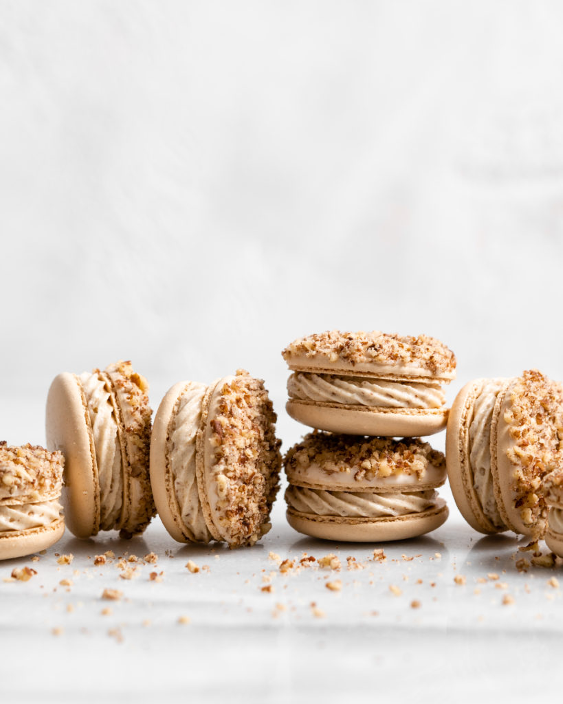 Maple pecan macarons using swiss method, filled with rich maple flavor, the macarons also have a maple buttercream that is speckled with little pecan bits, and a pecan crusted top