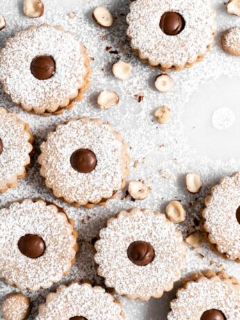 Flower shaped linzer cookies filled with nutella, sandwiched together, and dusted with confectioners sugar