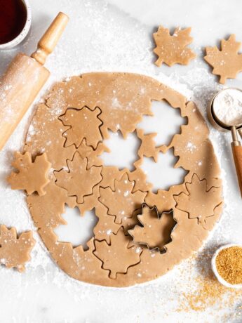 maple sugar cookie rolled out dough with cut out maple leaf cookies