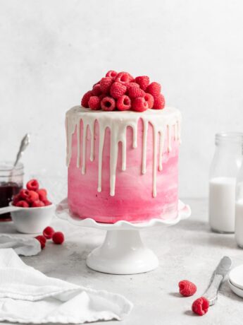 Pink Raspberry Layer Cake with white chocolate drip. Topped with fresh raspberries