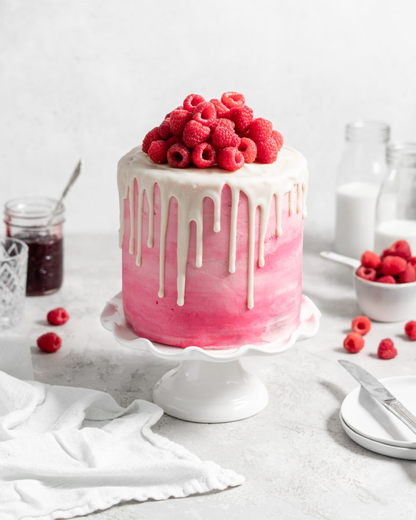 Pink Raspberry Layer Cake with white chocolate drip. Topped with fresh raspberries