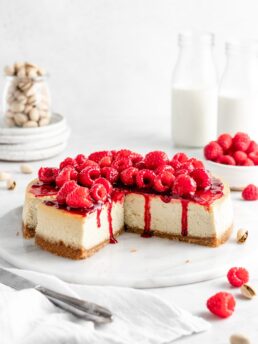 Creamy and rich pistachio cheesecake topped with raspberry sauce and fresh juicy raspberries