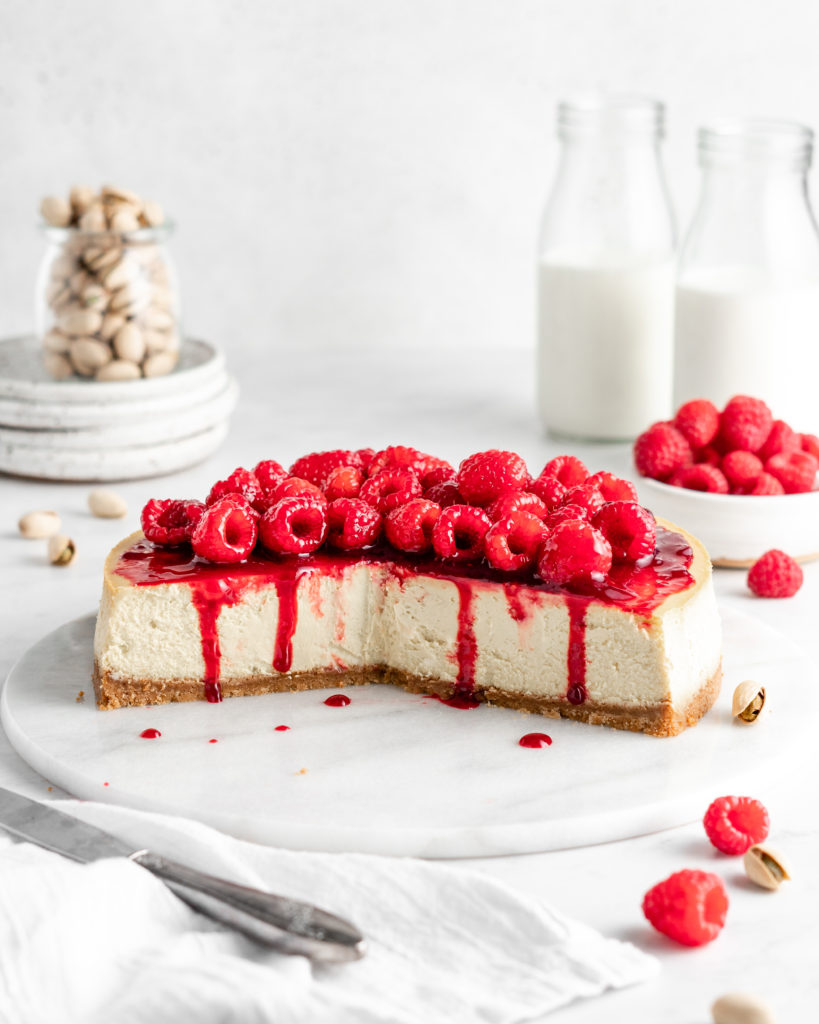 Creamy and rich pistachio cheesecake topped with raspberry sauce and fresh juicy raspberries
