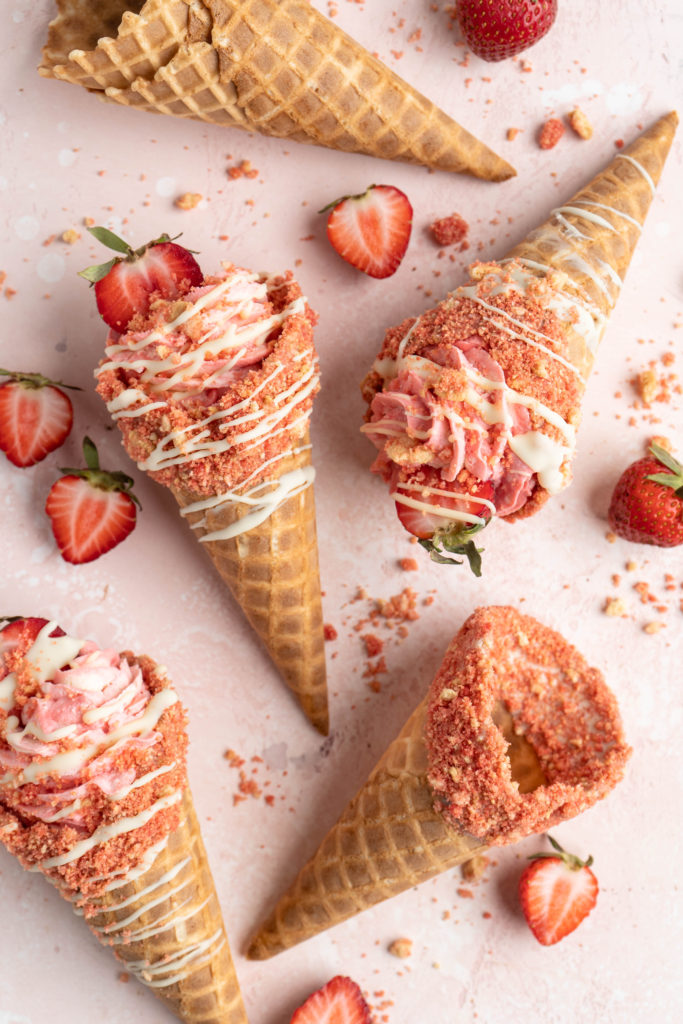 strawberry crunch cheesecake cone on a pink background